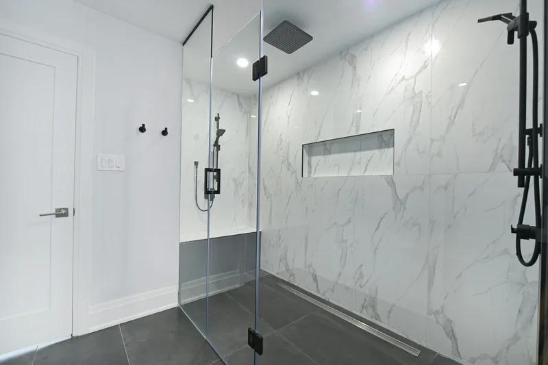 Moderne inloopdouche met marmerlook wandtegels en zwart sanitair