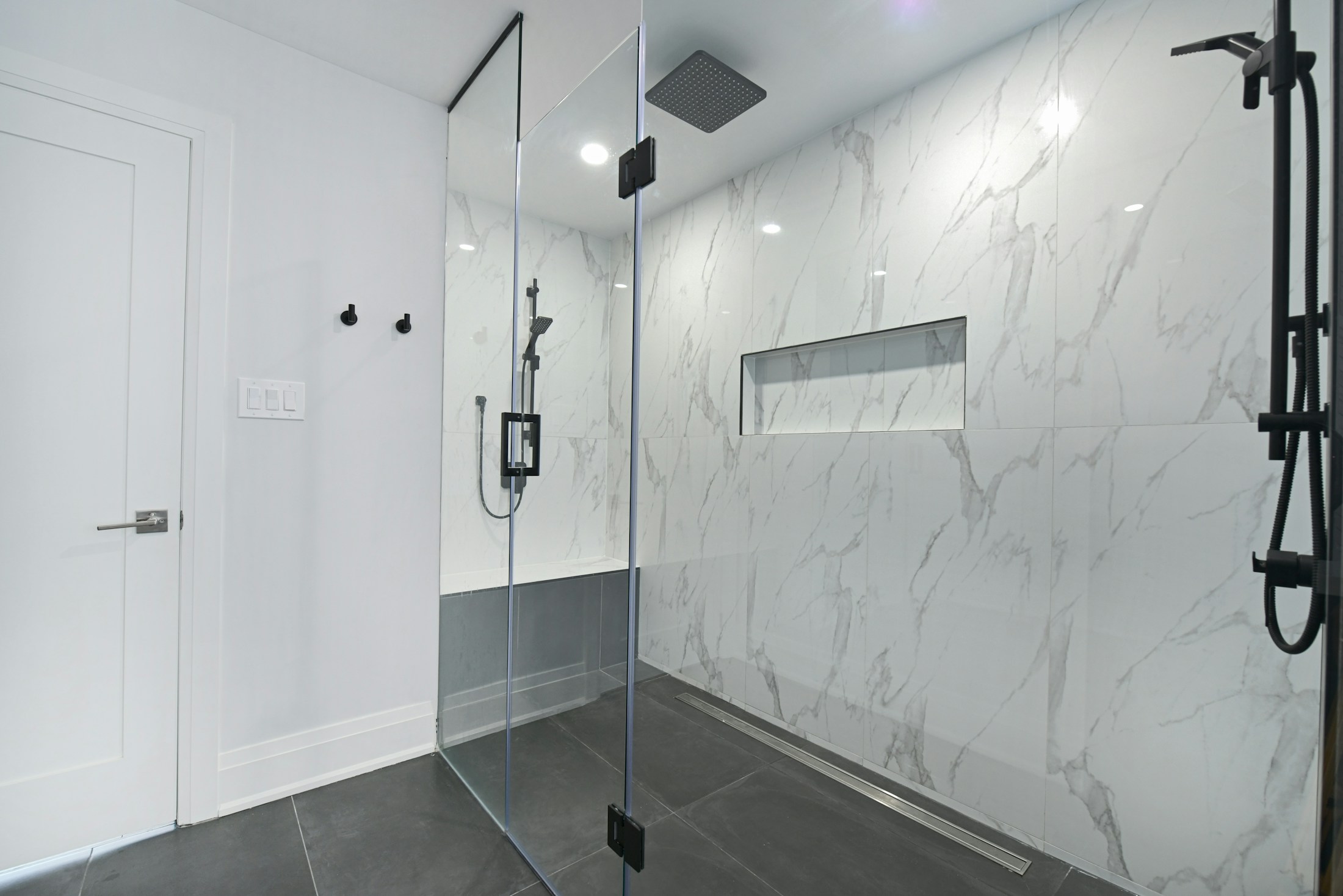 Moderne inloopdouche met marmerlook wandtegels en zwart sanitair